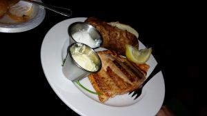 Jack Daniels salmon with a wedge of lemon and a baked potato with dishes of butter and sour cream.