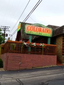 A big neon sign reading "Colorado Steakhouse"